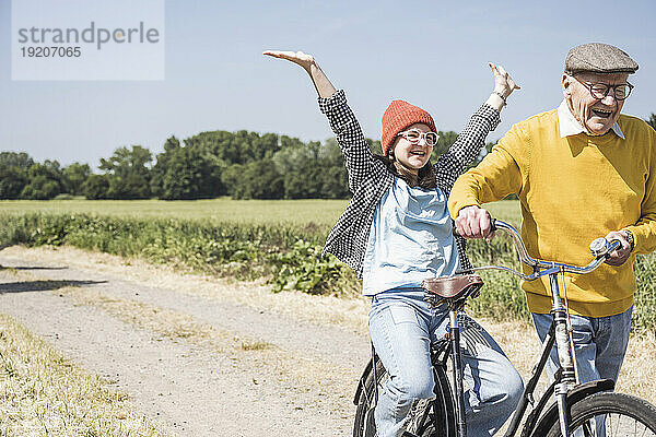Glücklicher älterer Mann mit Enkelin  der sich auf dem Fahrrad vergnügt