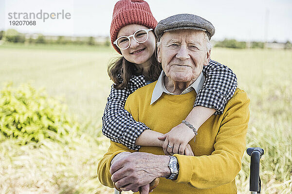Glückliches Mädchen mit Großvater auf dem Feld
