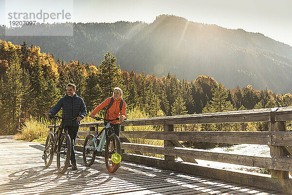 Österreich  Alpen  Paar mit Mountainbikes überquert eine Brücke
