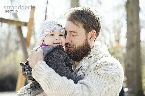 Zärtlicher Vater trägt Tochter im Park