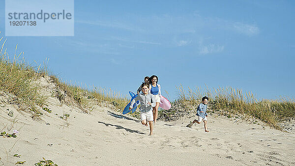 Glückliche Familie läuft am Strand unter freiem Himmel