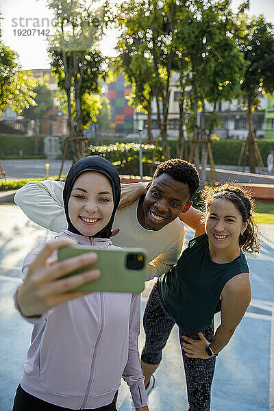 Lächelnde Frau macht Selfie mit Freunden am Sportplatz