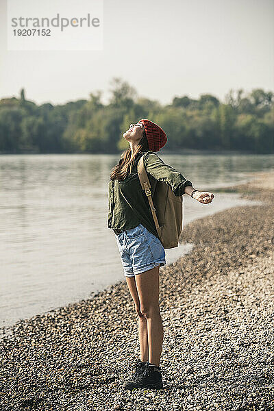 Glückliche junge Frau  die am Flussufer steht