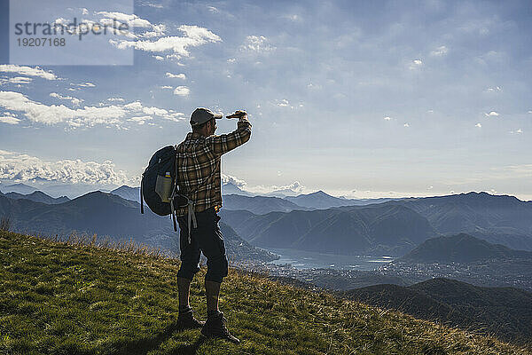 Mature hiker shielding eyes standing on mountain