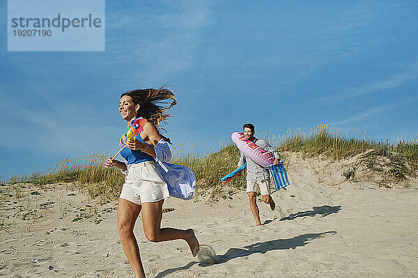 Glückliche Frau und Mann laufen an einem sonnigen Tag am Strand