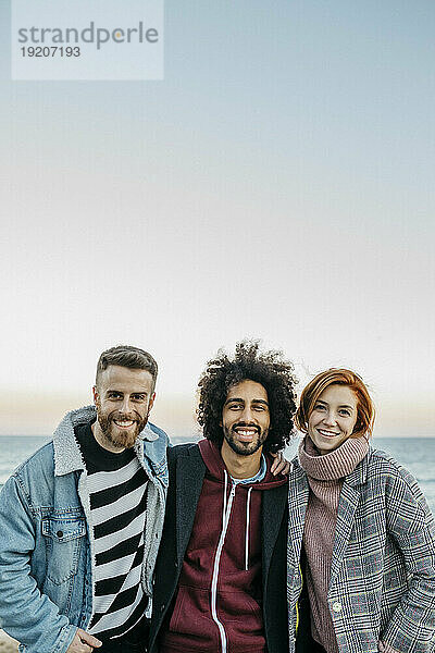 Porträt von drei glücklichen Freunden am Meer