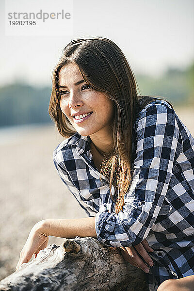 Lächelnde junge Frau  die draußen sitzt