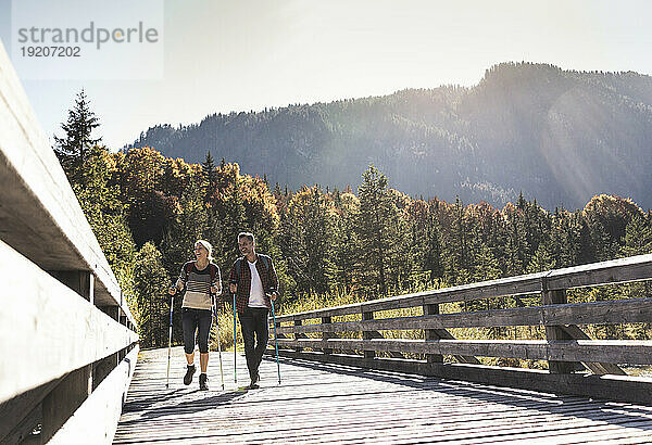 Österreich  Alpen  Paar überquert Brücke und geht mit Wanderstöcken