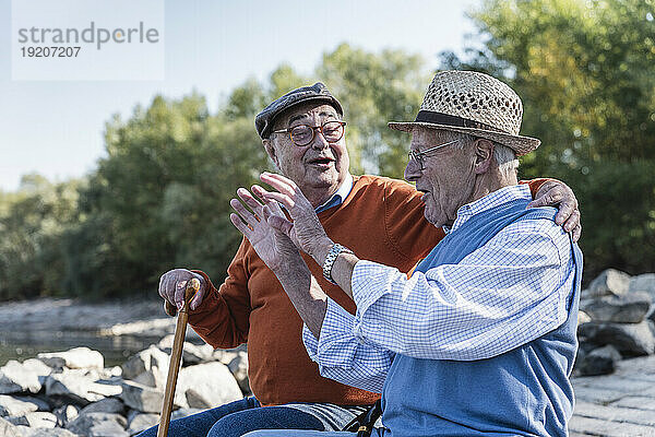 Zwei alte Freunde sitzen am Flussufer und haben Spaß