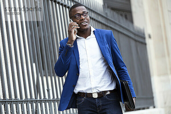 Junger Geschäftsmann trägt blaue Anzugjacke und benutzt Smartphone