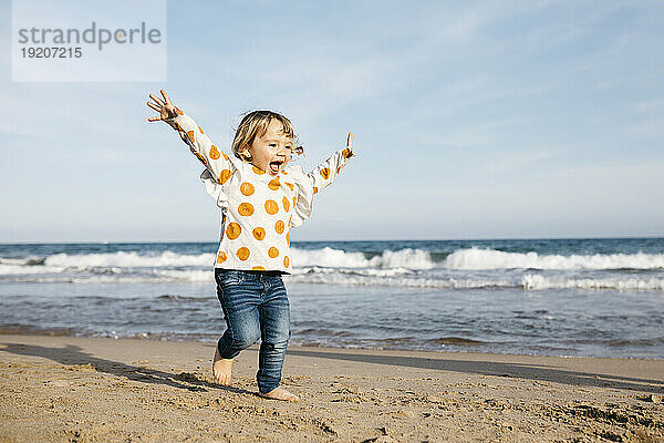 Glückliches kleines Mädchen  das barfuß am Strand läuft