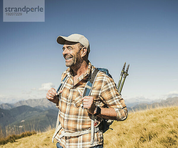 Happy mature hiker with backpack at sunny day