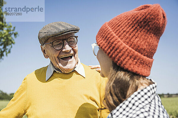 Fröhlicher älterer Mann mit Enkelin mit Strickmütze