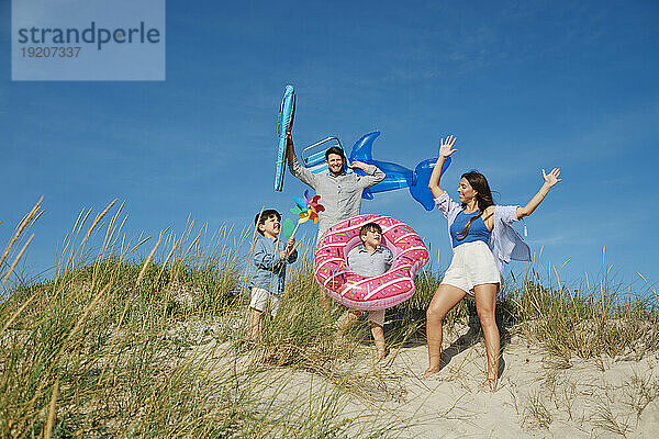 Glückliche Familie  die an einem sonnigen Tag Spaß hat und unter dem Himmel tanzt