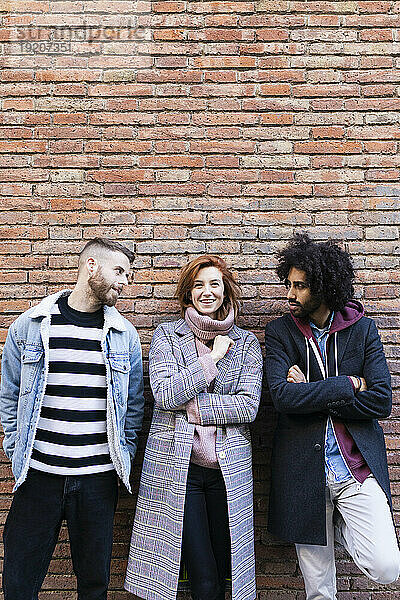 Porträt von drei Freunden  die an einer Mauer stehen