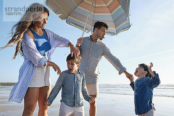 Glückliche Familie  die an einem sonnigen Tag am Strand genießt