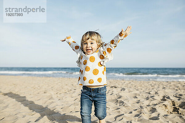Porträt eines glücklichen kleinen Mädchens  das am Strand läuft