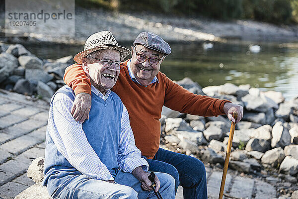 Zwei alte Freunde sitzen am Flussufer und haben Spaß