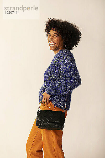 Cheerful woman with sling bag against white background