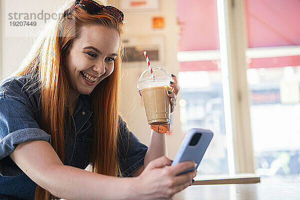 Lächelnde Geschäftsfrau benutzt Smartphone im Café