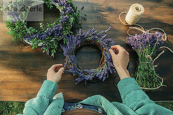 Hand of woman making lavender wreath on table