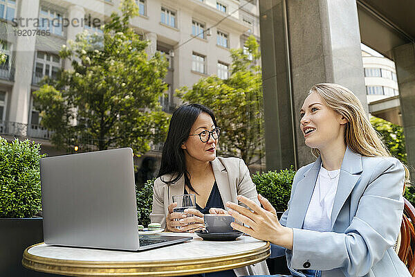 Geschäftsfrau diskutiert mit Partner im Straßencafé