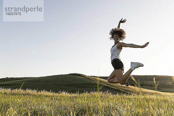 Fröhliche Frau springt an einem sonnigen Tag