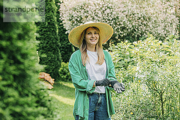 Lächelnde Frau mit Handschuhen im Garten