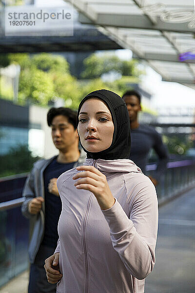 Frau mit Hijab joggt mit Freunden