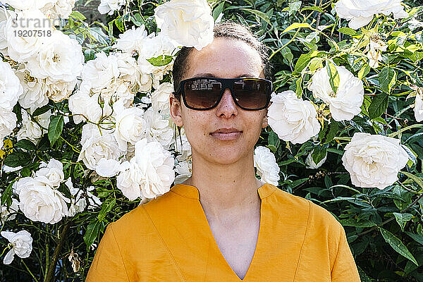 Frau mit Sonnenbrille inmitten weißer Blumen