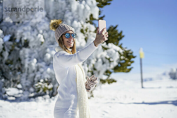 Lächelnde Frau macht Selfie im Winterschnee