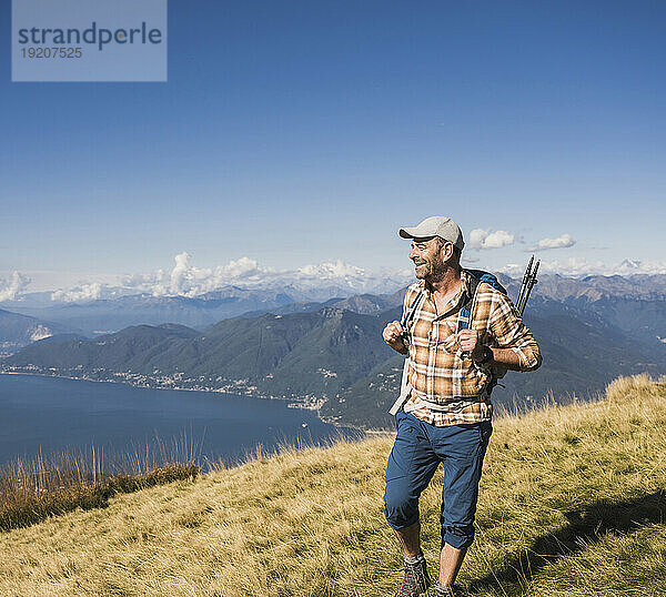 Lächelnder Mann  der an einem sonnigen Tag auf dem Berg spaziert