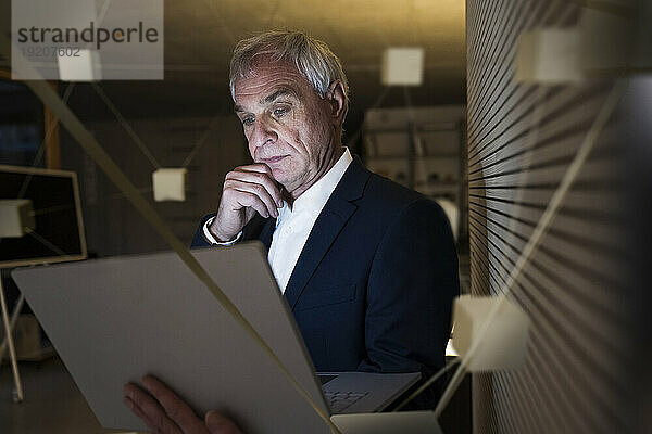 Digitales zusammengesetztes Bild eines nachdenklichen Geschäftsmannes mit Laptop im Büro