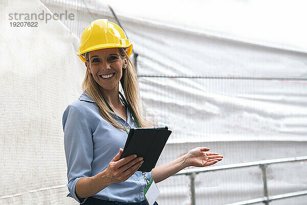 Lächelnder Ingenieur gestikuliert mit Tablet-PC