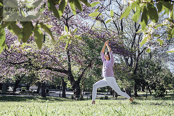 Teenage girl practicing yoga at park in bloom