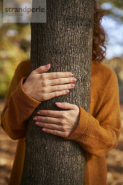 Frau umarmt Baum im Wald