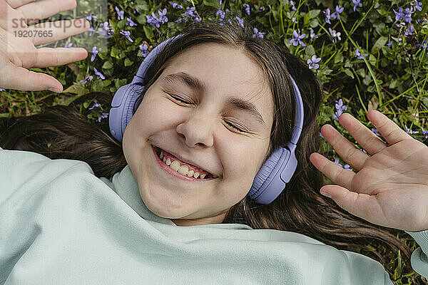 Lächelndes Mädchen  das im Garten Musik hört