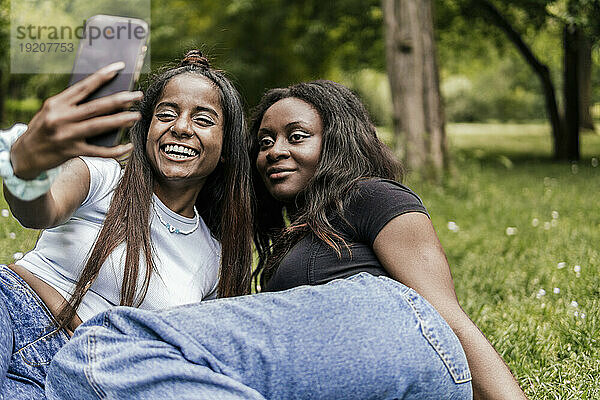 Lächelnde Freunde  die im Park ein Selfie mit dem Smartphone machen