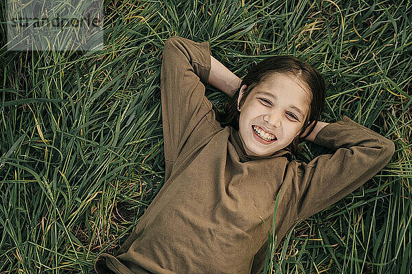 Lächelnder Junge liegt auf Gras im Feld