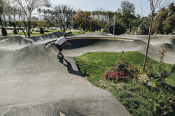 Mann übt an sonnigem Tag mit Skateboard im Park