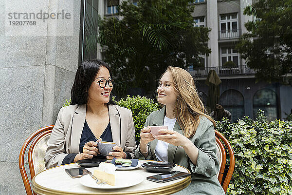 Lächelnde Geschäftspartner genießen Kaffee im Straßencafé