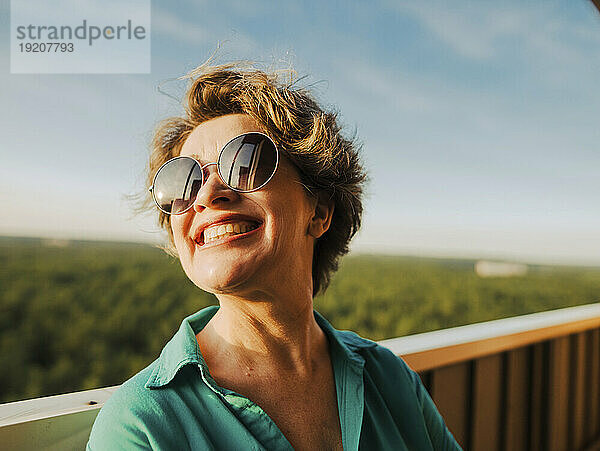 Lächelnde Frau mit Sonnenbrille an sonnigem Tag