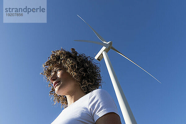Frau vor Windkraftanlage an sonnigem Tag