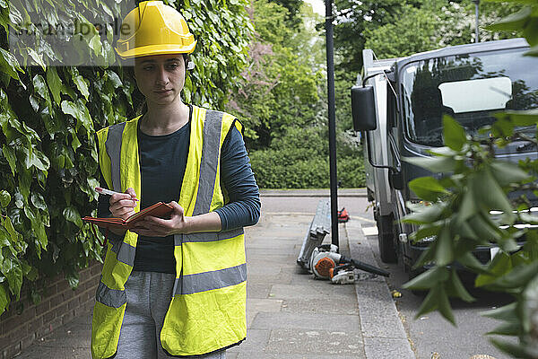 Arbeiter mit Schutzhelm untersucht umgestürzten Baum