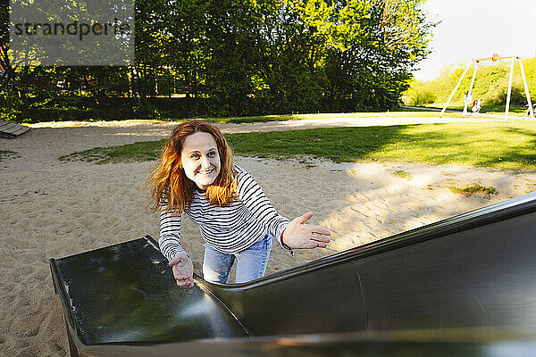 Smiling woman standing near slide in playground