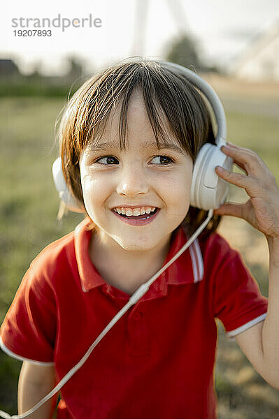 Fröhlicher Junge  der mit Kopfhörern Musik hört