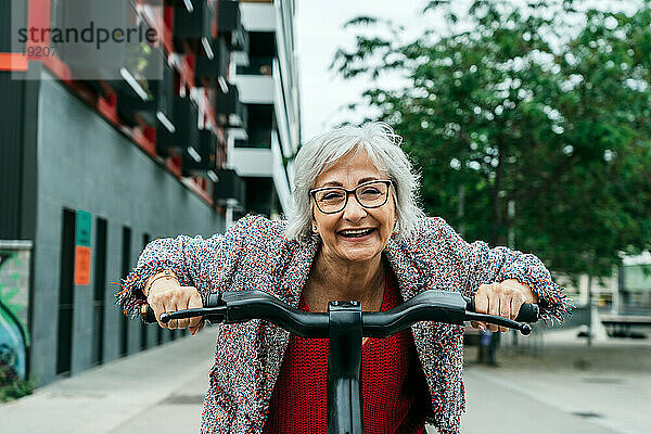 Glückliche Geschäftsfrau  die Spaß mit dem Fahrrad auf der Straße hat
