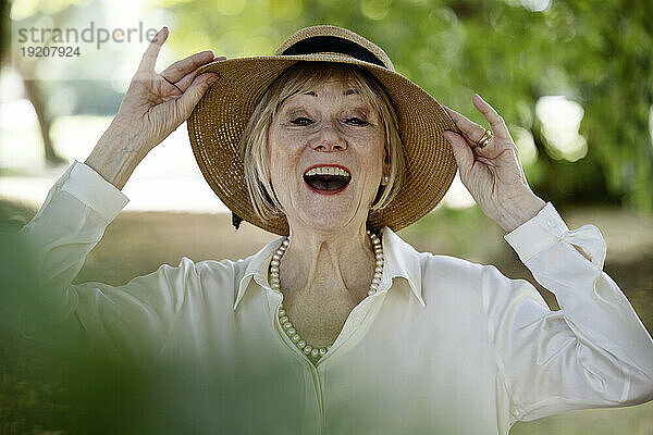 Fröhliche Frau mit Hut im Park