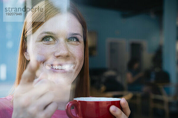 Lächelnde Frau hält Kaffeetasse im Café