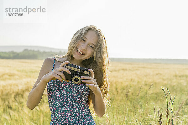 Lächelndes Mädchen mit Kamera auf dem Feld